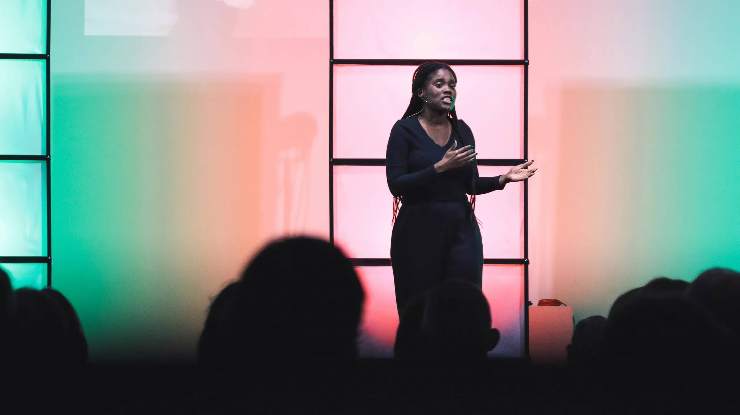 A speaker mid-sentence on a stage lit pink and green, the audience in silhouette below, cover of the Events & Corporate demo portfolio
