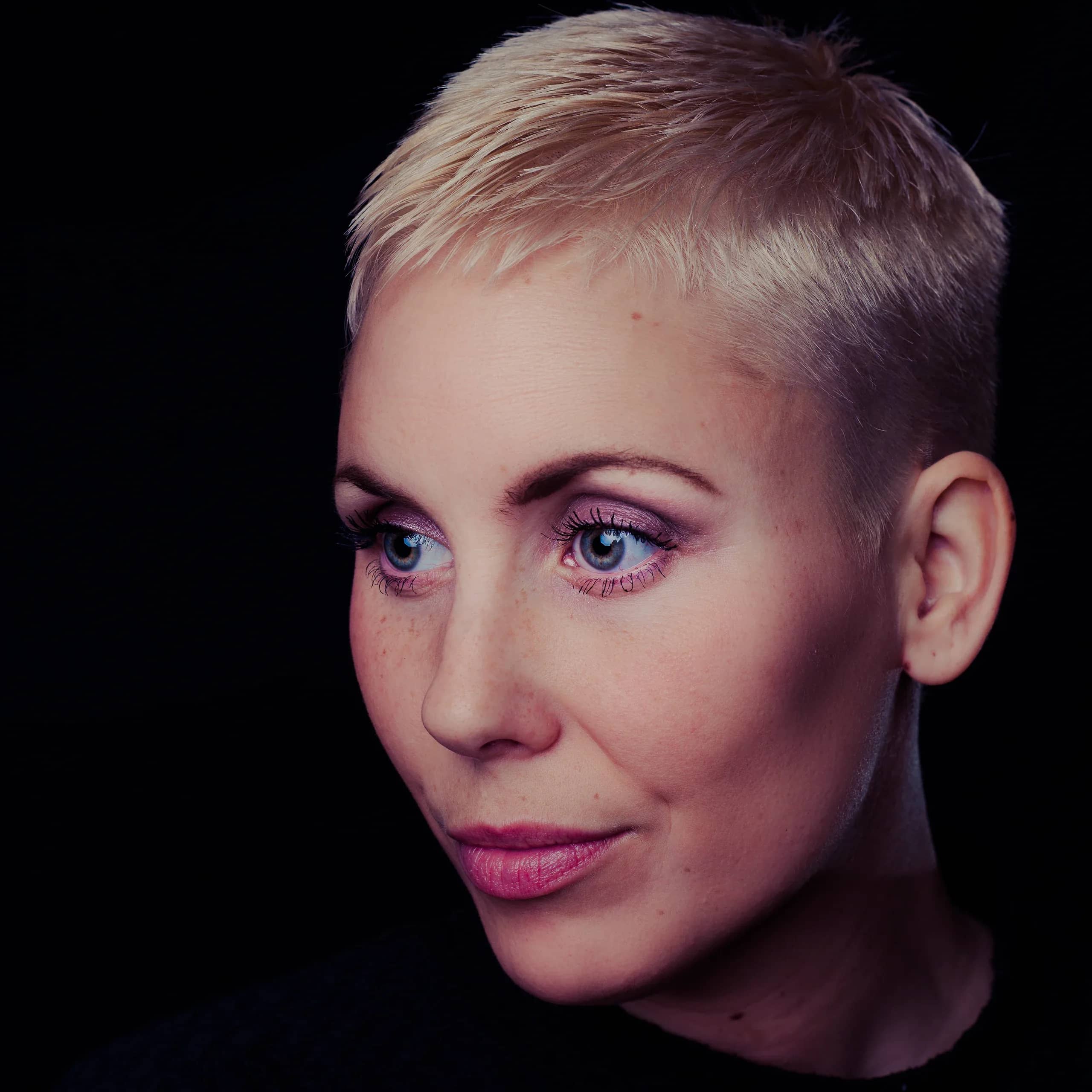 Close studio headshot of a woman with a short platinum crop, lit softly against black, cover of the Portraits & Headshots demo portfolio